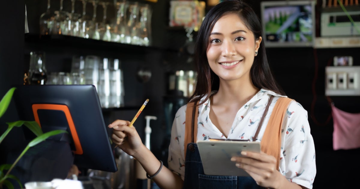Barista di kafe tersenyum sambil memegang menu