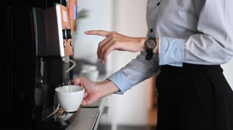 Wanita muda sedang membuat kopi dengan Dispenser Minuman Panas