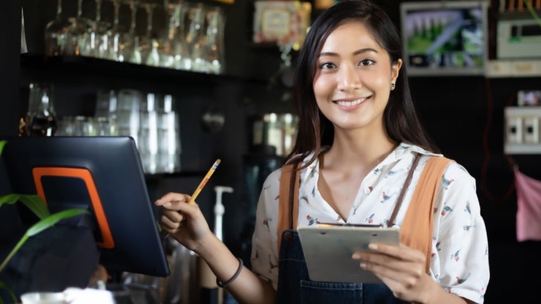 Barista di kafe tersenyum sambil memegang menu