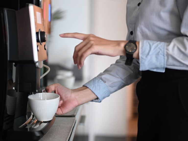Wanita muda sedang membuat kopi dengan Dispenser Minuman Panas