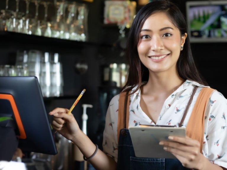 Barista di kafe tersenyum sambil memegang menu
